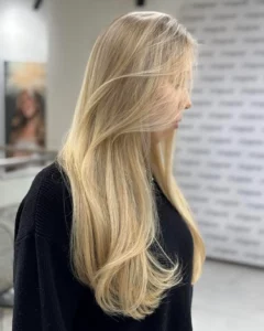 Długie, gładkie blond włosy po stylizacji, widok z boku w salonie fryzjerskim ufryzjerow.pl
